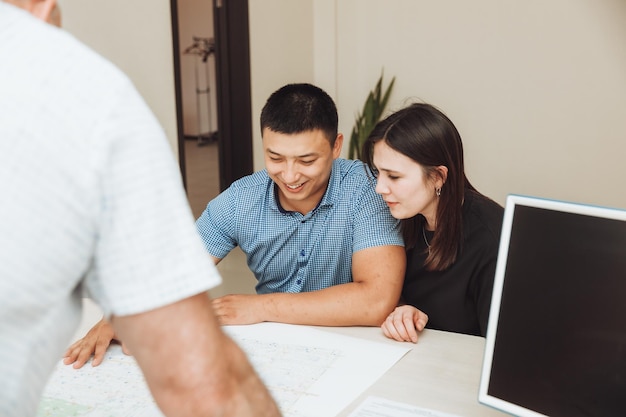 A happy couple signs a contract together in the office a man\
and a woman buy an apartment and sign a contract