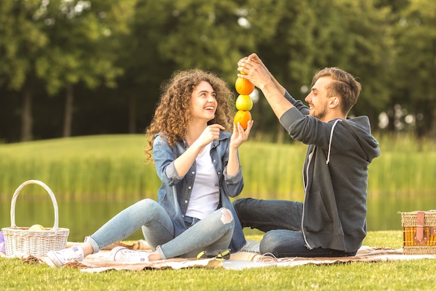 The happy couple sit the grass and hold fruits