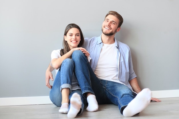 The happy couple sitting on the background of the gray wall.