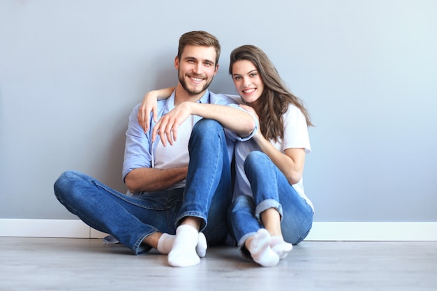 The happy couple sitting on the background of the gray wall.