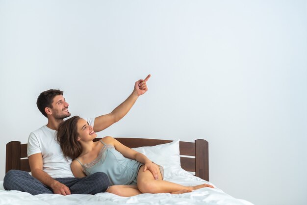 The happy couple sitting on the bed and gesturing