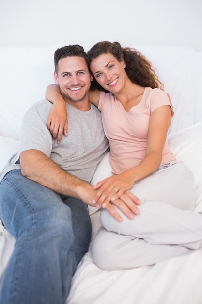 Happy couple sitting on bed