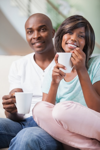 Happy couple sitting on couch having coffee 