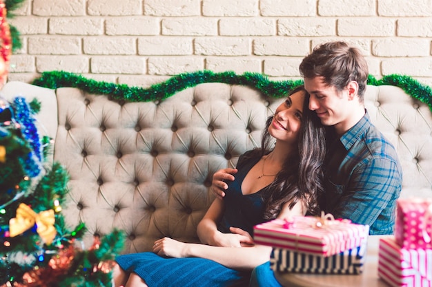 Happy couple sitting near Christmas tree