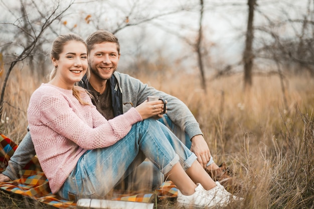 Happy Couple Sitting On Picnic Blanket Outdoors