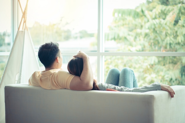 Happy couple sitting on the sofa and being a man embracing his girlfriend with love in the living room and relax.