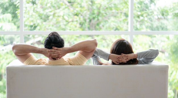 Happy couple sitting on the sofa and being a man embracing his girlfriend with love in the living room and relax.