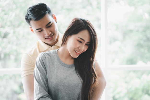 Happy couple sitting on the sofa and being a man teases his girlfriend with love in the living room