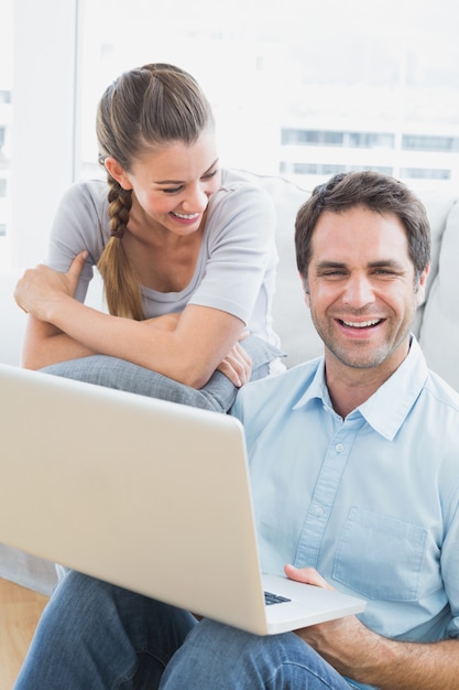 Happy couple sitting on the sofa using laptop 