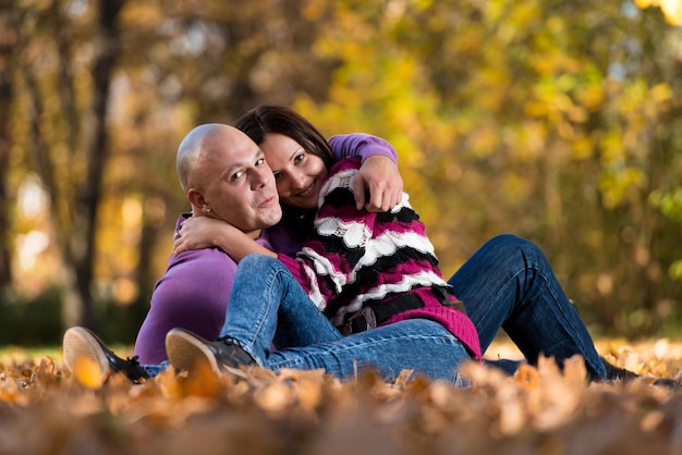 秋の森の中で一緒に座っている幸せなカップル