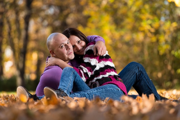 Happy Couple Sitting Together In The Woods During Autumn