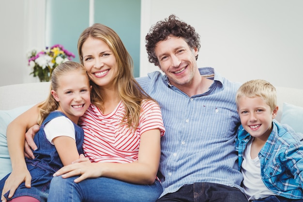 Happy couple sitting with children on sofa