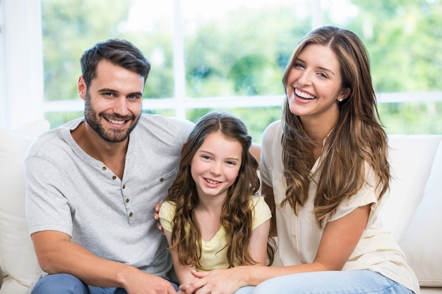 Happy couple sitting with daughter on sofa