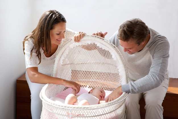 Happy couple smiling with baby in cot