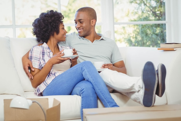 Photo happy couple on the sofa drinking coffee in the living room