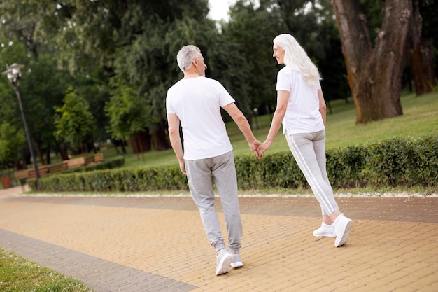 Happy couple of sporty pensioners walking in the park and smiling