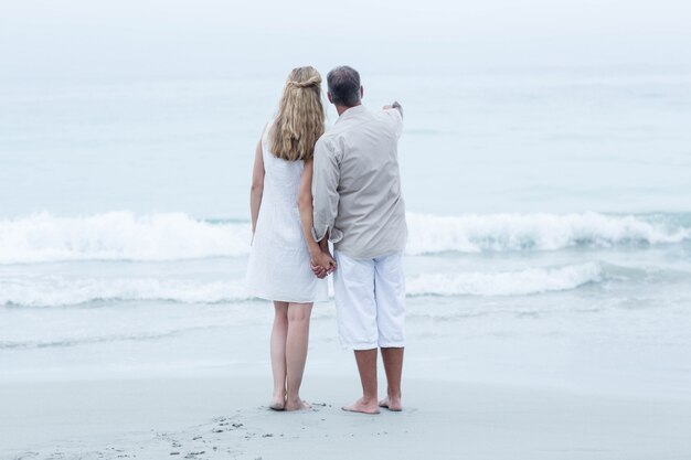 Happy couple standing by the sea and holding hands