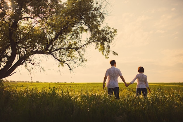 Happy couple standing in the field at the sunset