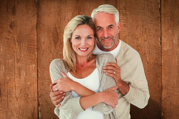 Photo happy couple standing and hugging against wooden planks