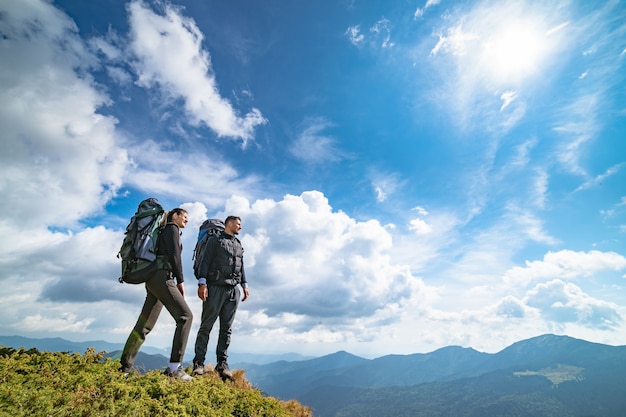 The happy couple standing on the mountain with a picturesque cloudscape