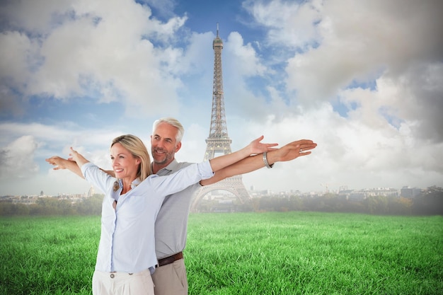 Счастливая пара, стоящая с протянутыми руками против эйфелевой башни