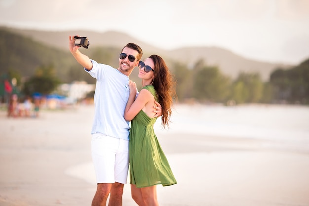 Photo happy couple taking a photo on white beach on honeymoon holidays