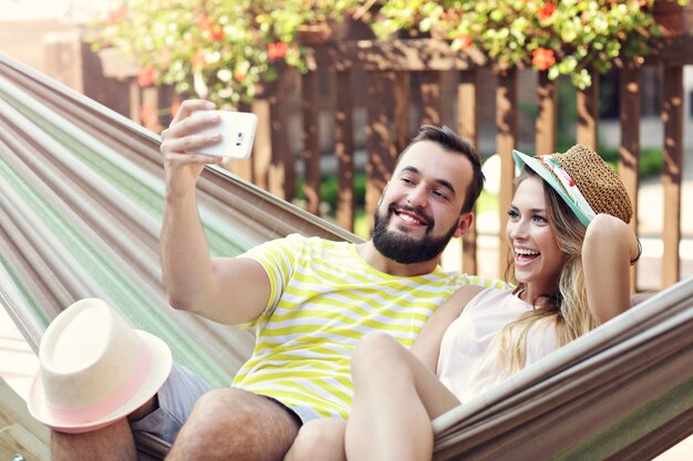 happy couple taking selfie on hammock