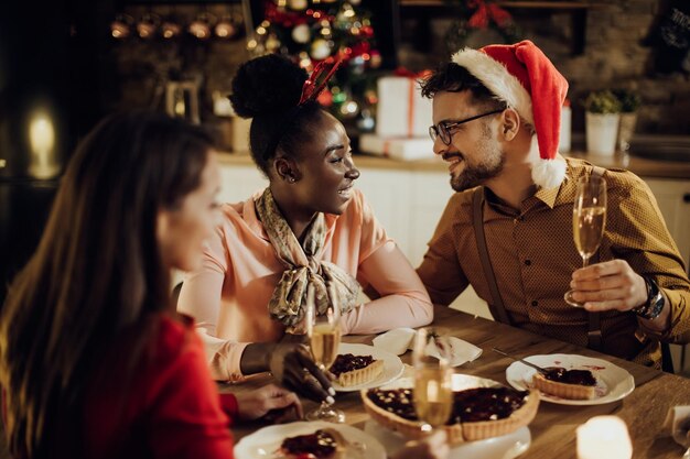 ダイニングルームでクリスマスを祝っている間、シャンパンを話したり飲んだりして幸せなカップル