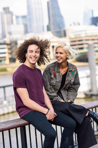 Happy couple talking sitting near River Thames.