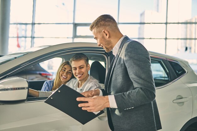 Coppia felice testare la nuova automobile prima di firmare un contratto di vendita del veicolo