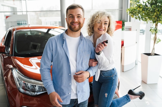 Happy couple and their new car in dealership