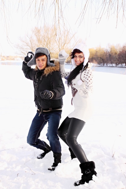 Photo happy couple throwing snowballs in the park