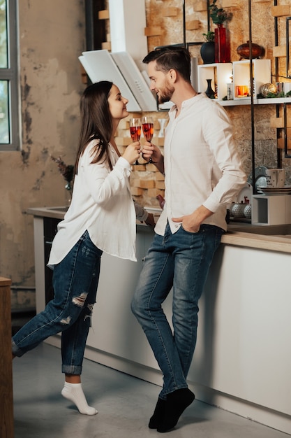 Happy couple toasting champagne glasses in kitchen at home. Celebration in kitchen.