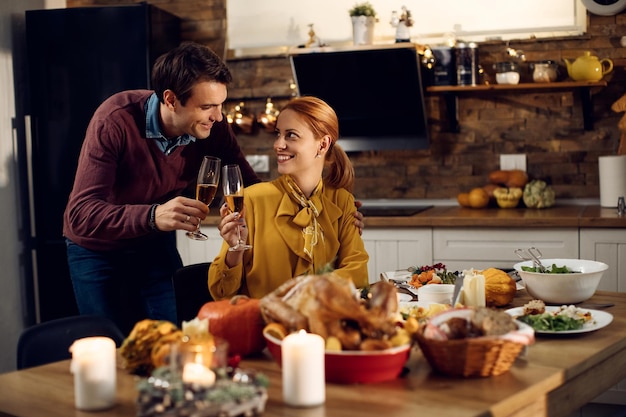 Happy couple toasting with Champagne during Thanksgiving meal in dining room