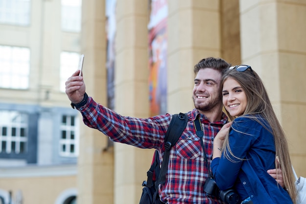 Happy couple of tourists taking selfie in showplace of city