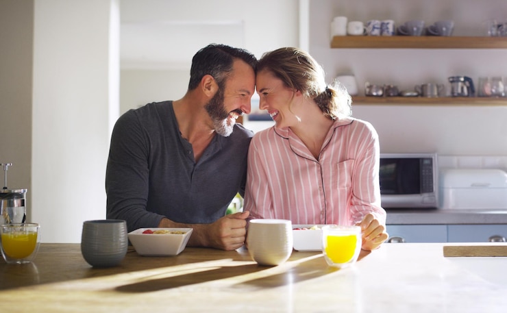Photo happy couple trust or eating breakfast together with love diet or juice in meal in home kitchen romantic people forehead or morning snack for bonding support or food in healthy marriage for care
