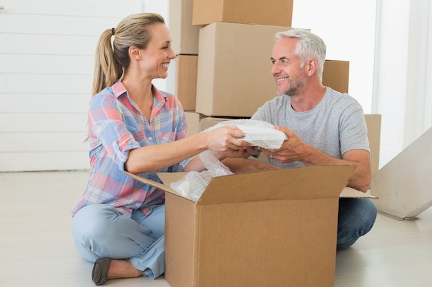 Happy couple unpacking cardboard moving boxes