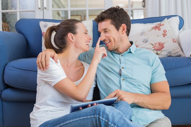 Happy couple using digital tablet in living room