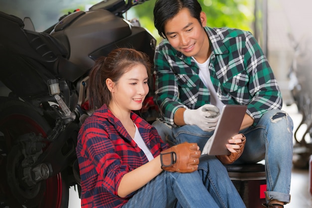 Happy couple using digital tablet at Repairing and custom motorcycles shop