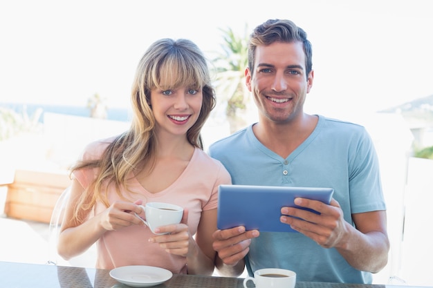 Happy couple using digital tablet while having coffee