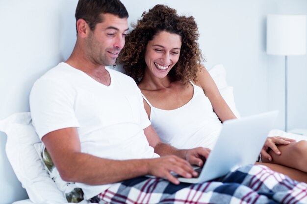 Photo happy couple using laptop on bed