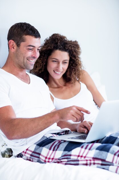 Happy couple using laptop on bed