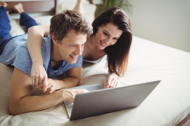 Happy couple using laptop on bed