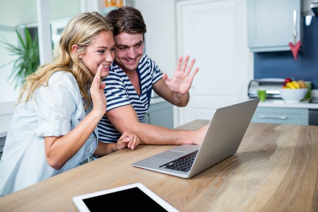 Happy couple using laptop in the kitchen