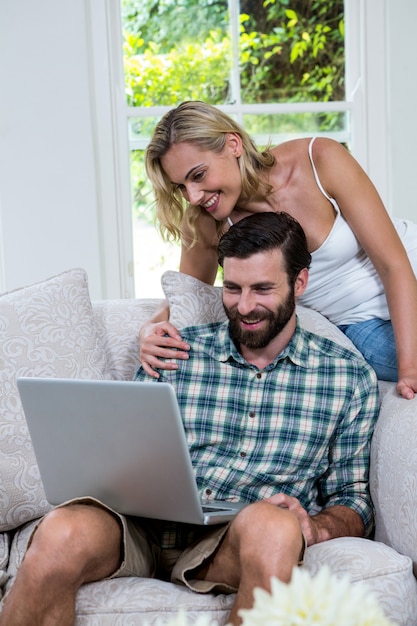 Happy couple using laptop in sitting room