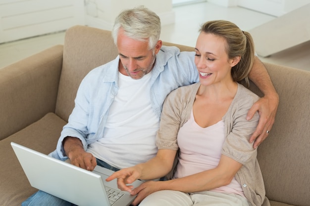 Happy couple using the laptop together on the couch