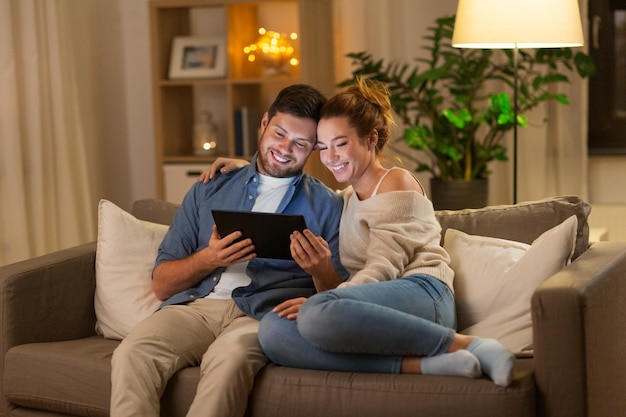 Photo happy couple using tablet pc at home in evening