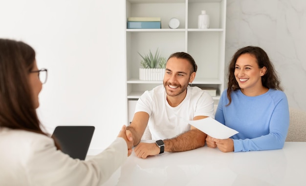Happy couple visiting doctor shaking hand satisfied with results