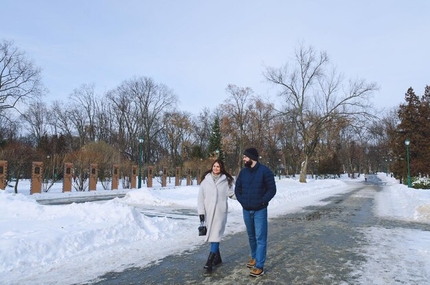 Happy couple walking in city. Young business man in a blue jacket, beard. cute woman in long coat.