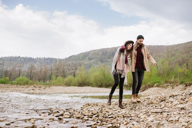 Happy couple walking down the river in the mountains